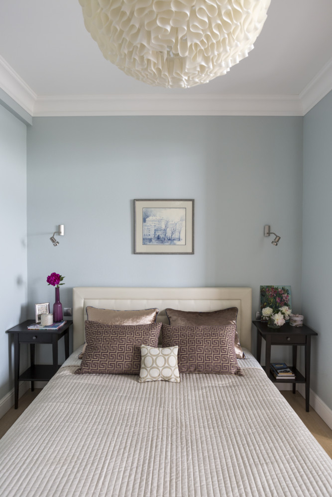 Лёгкая холодная колористическая гамма серо-голубых стен, светлое изголовье кровати, тёмные тумбочки — всё просто.